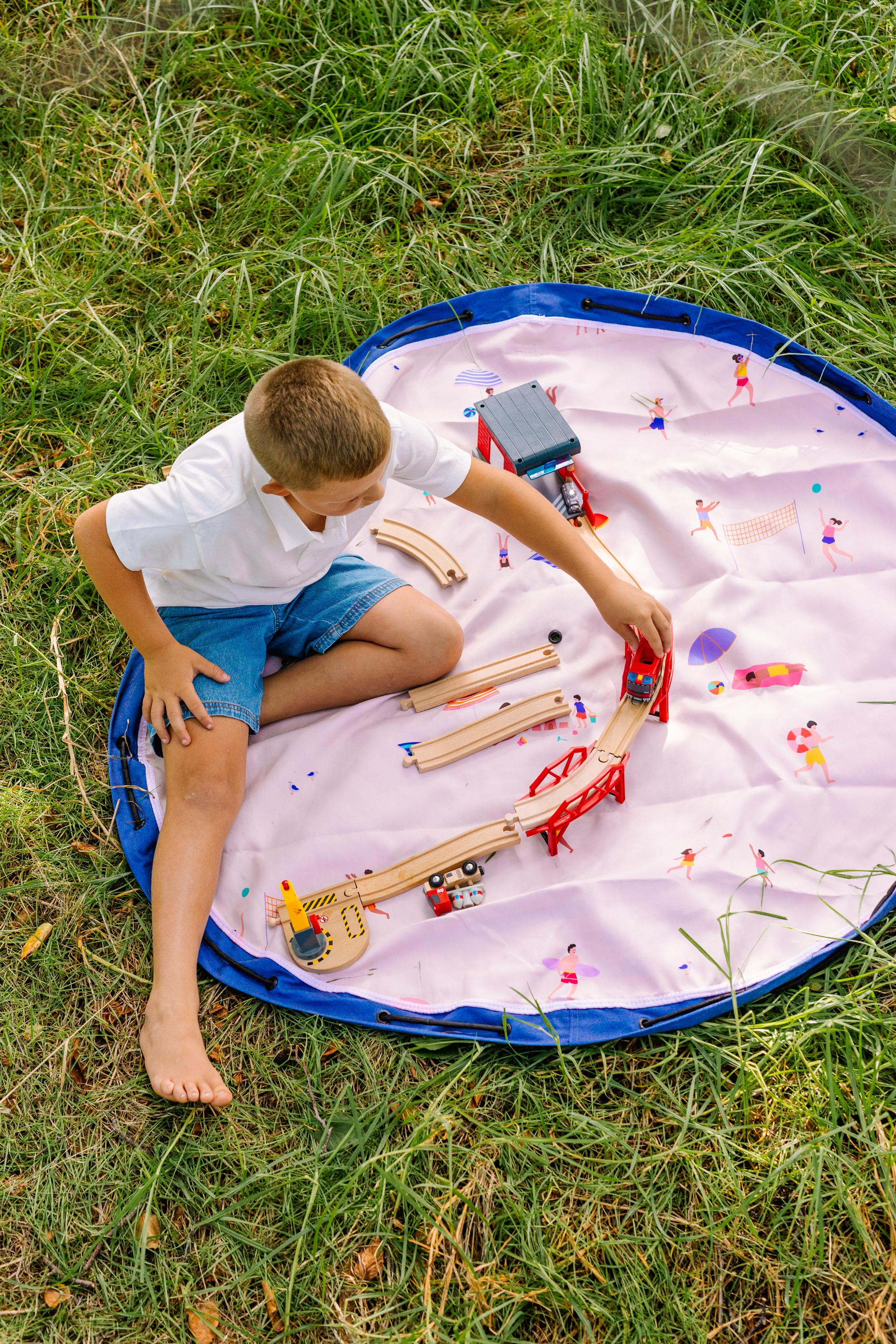 Beach outdoor storage bag, child is sitting on the mat, playing with a bridge construction
