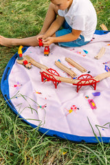 Beach outdoor storage bag, child is playing on the mat outside with a wooden toy construction