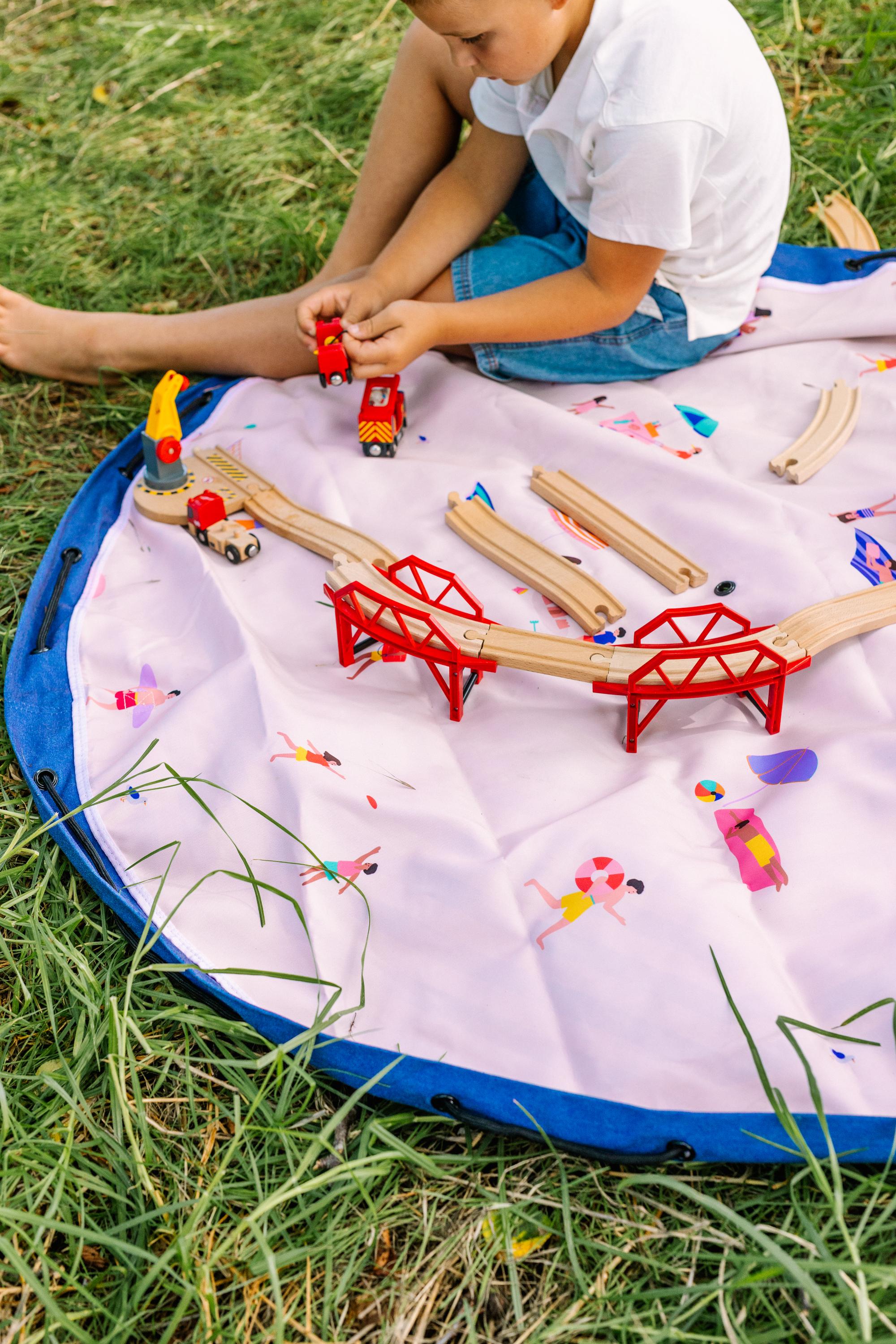 Beach outdoor storage bag, child is playing on the mat outside with a wooden toy construction
