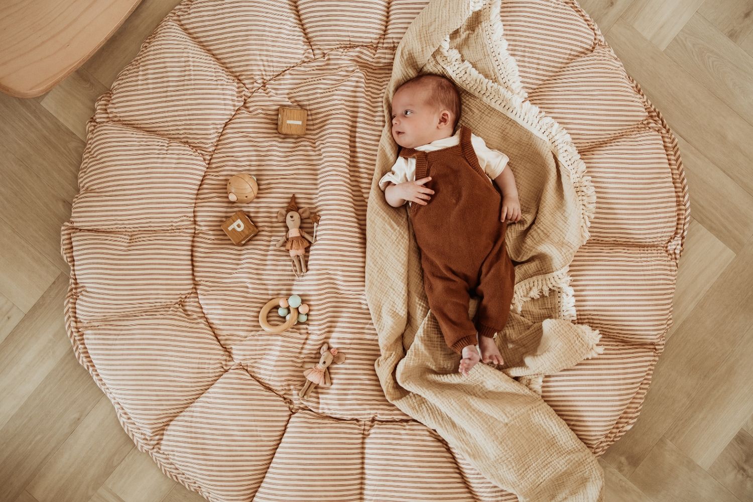 bloom stripes brown babymat, open, baby is lying on the mat, looking at wooden toys