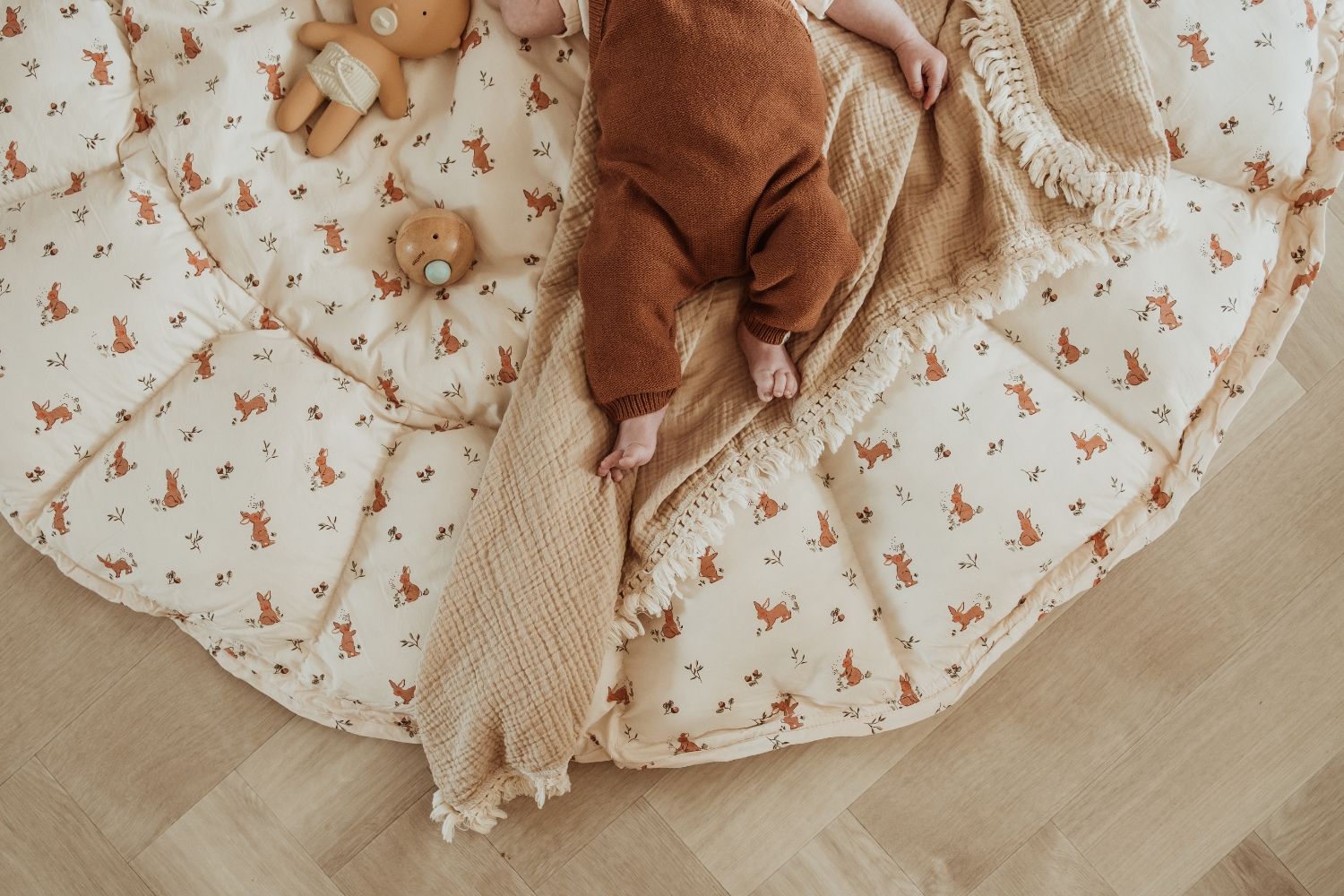 bloom rabbit babymat, open on floor, baby is lying on a blanket on the babymat