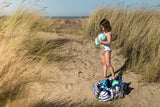 pirate outdoor playmat, young girl standing in sand dunes, playing with beach toys, storage bag is on the sand