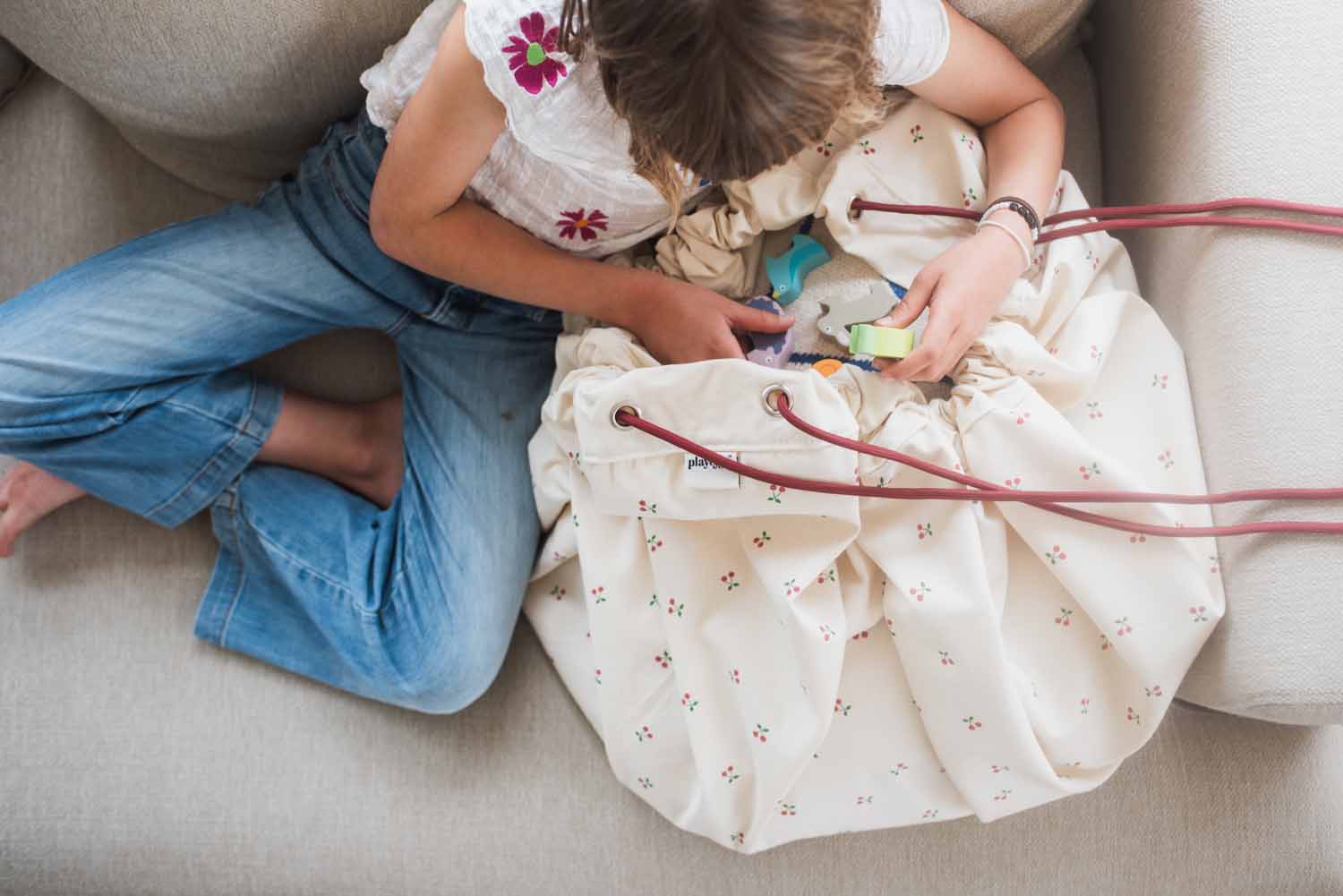 cherry cherry toy storage bag, child puts toys in the bag while sitting on the sofa