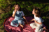 pic nic outdoor playmat, children are eating cookies while sitting on the mat outside in the grass