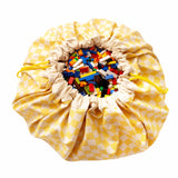 vichy yellow toy storage bag, closed, filled with lego