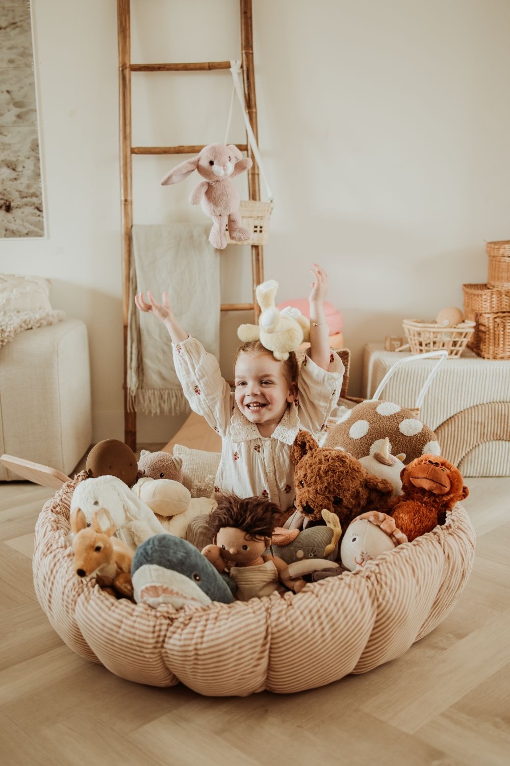 bloom stripes brown babymat, crib, raised edges, filled with cuddles, child is sitting in the crib, playing with the cuddles