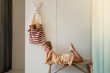 toto bunny, hanging on wall, filled with cuddles, child is laying on a wooden bench, looking into the camera