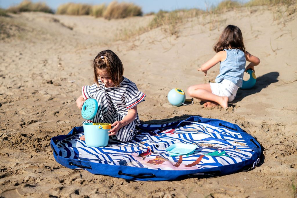 pirate outdoor playmat, two children playing on a sandy beach with a sand pirate illustrated mat.