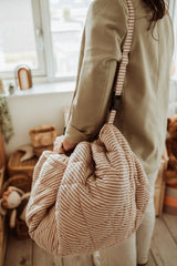 soft stripes brown organic babymat, person is carrying the bag with the shoulder strap