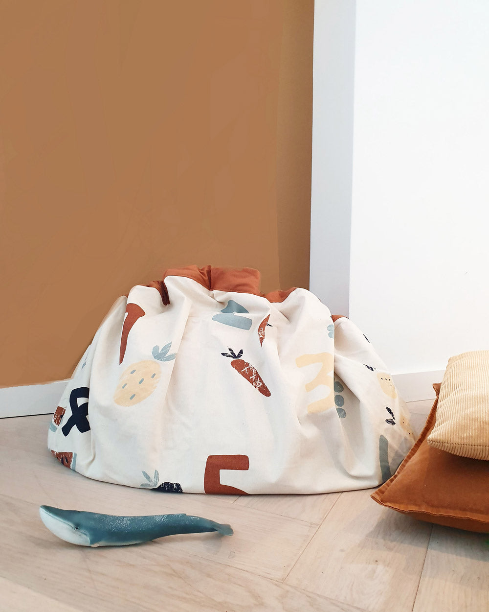 veggie numbers storage bag, closed on floor, next to pillows and cuddle whale