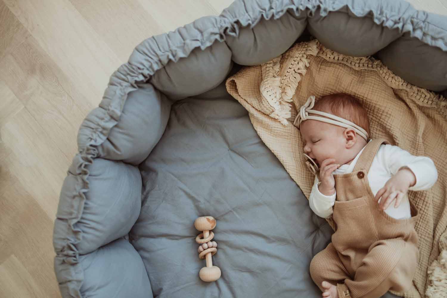 Bloom dusty blue organic babymat, little baby sleeping on mat on blanket, raised edges
