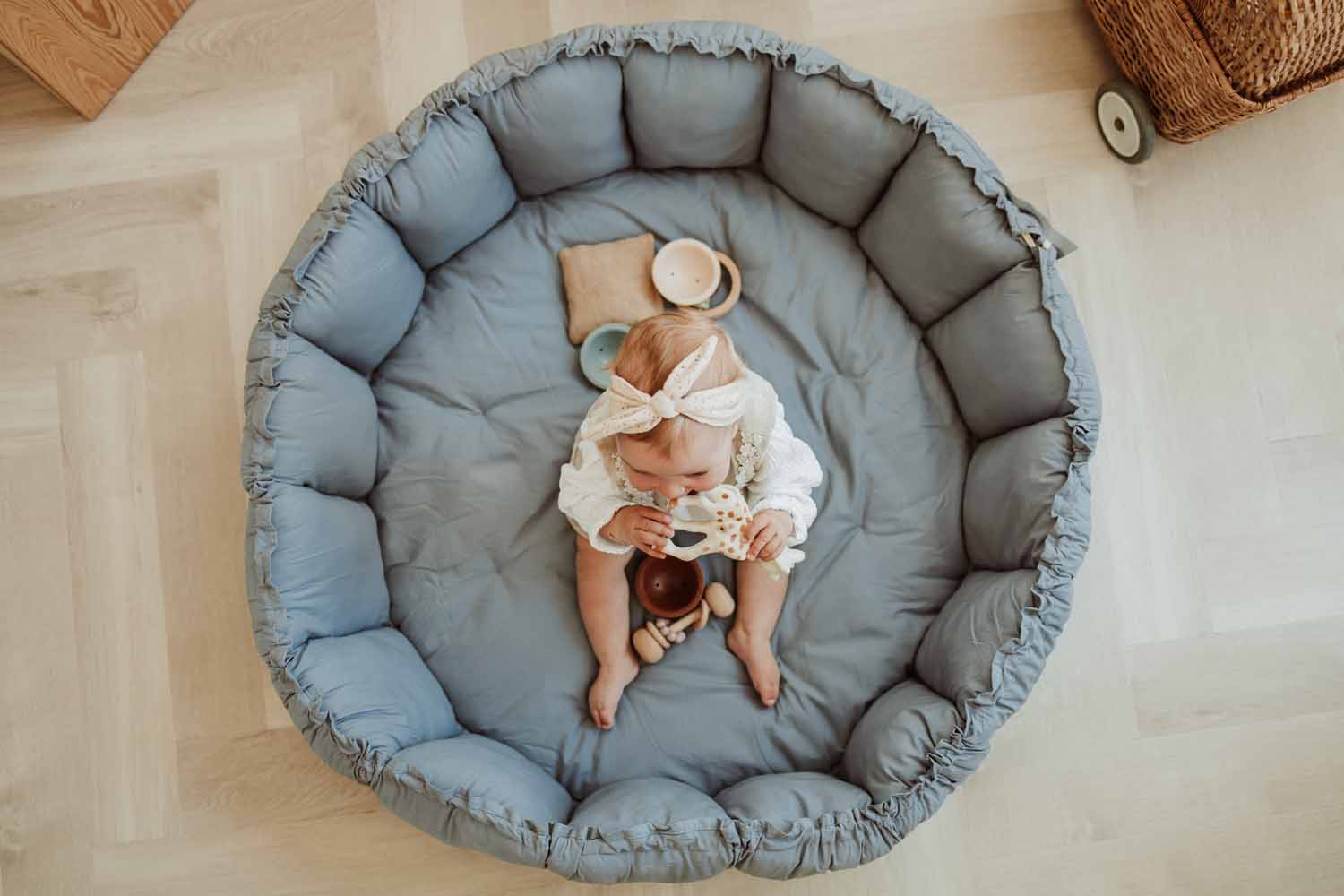 Bloom dusty blue organic babymat, raised edges, baby sitting on mat and playing with Sophie la Giraffe