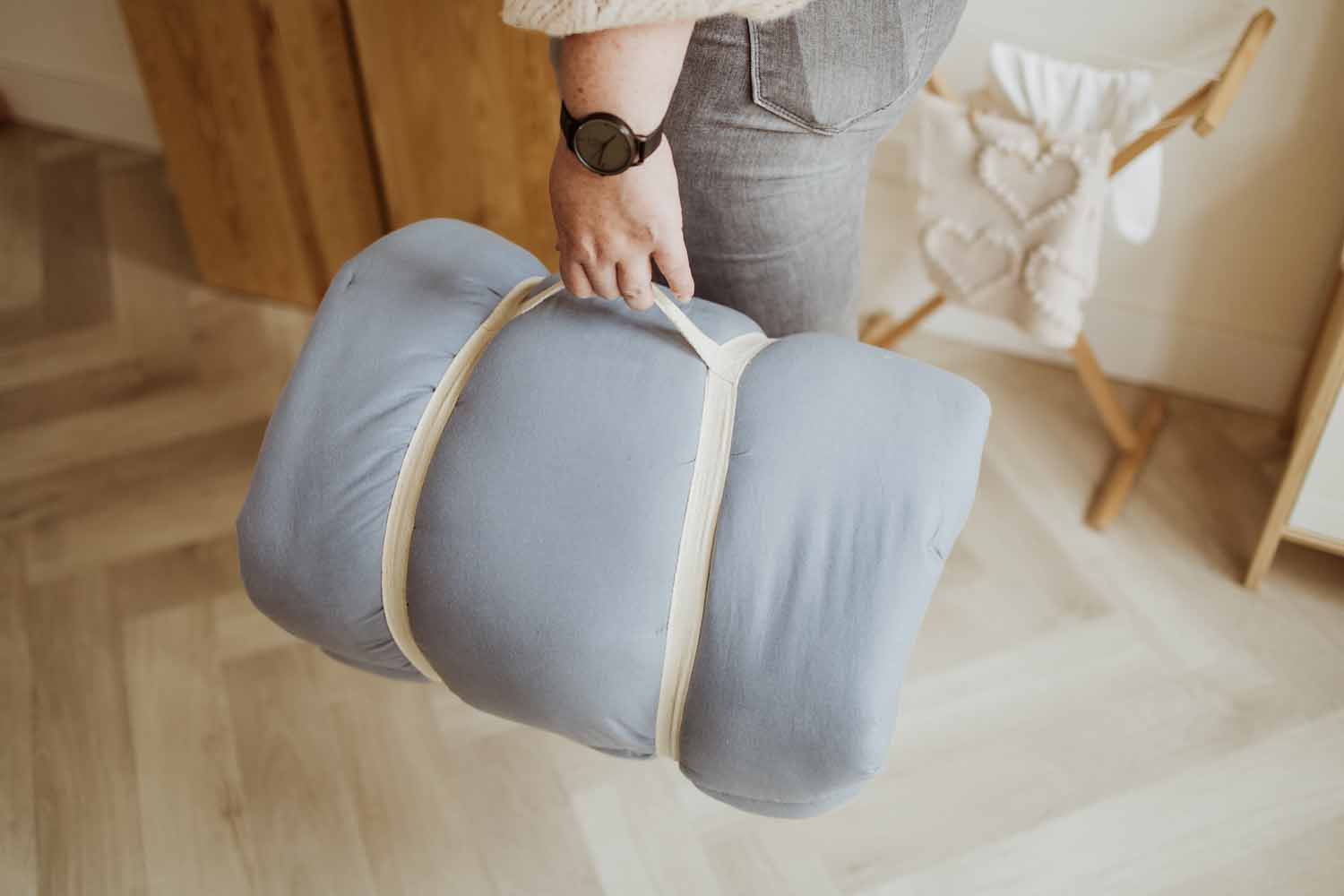 Bloom dusty blue organic babymat, detail picture of closed mat, person carrying it like a bag in its hand