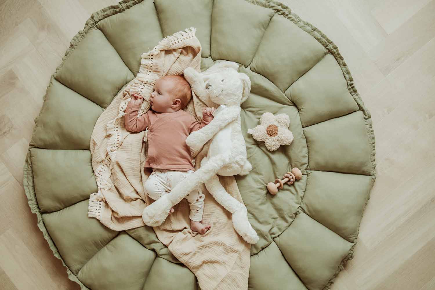 Bloom meadow green organic babymat, little baby lying on open mat on blanket next to soft cuddle