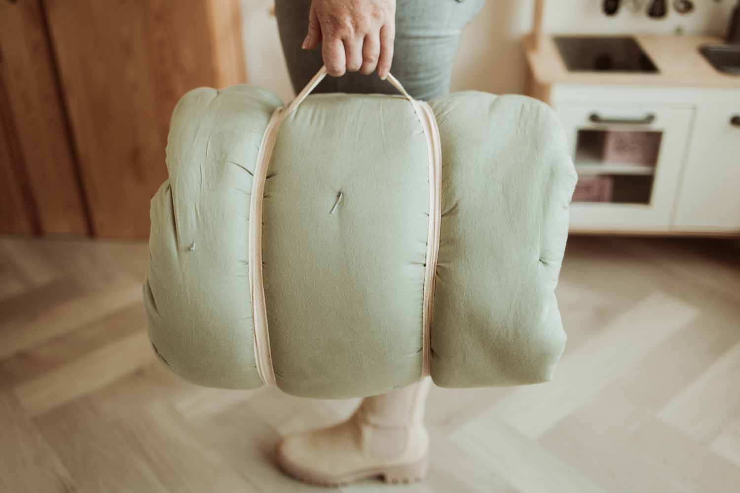 Bloom meadow green organic babymat, closed mat, person carrying the mat as a bag