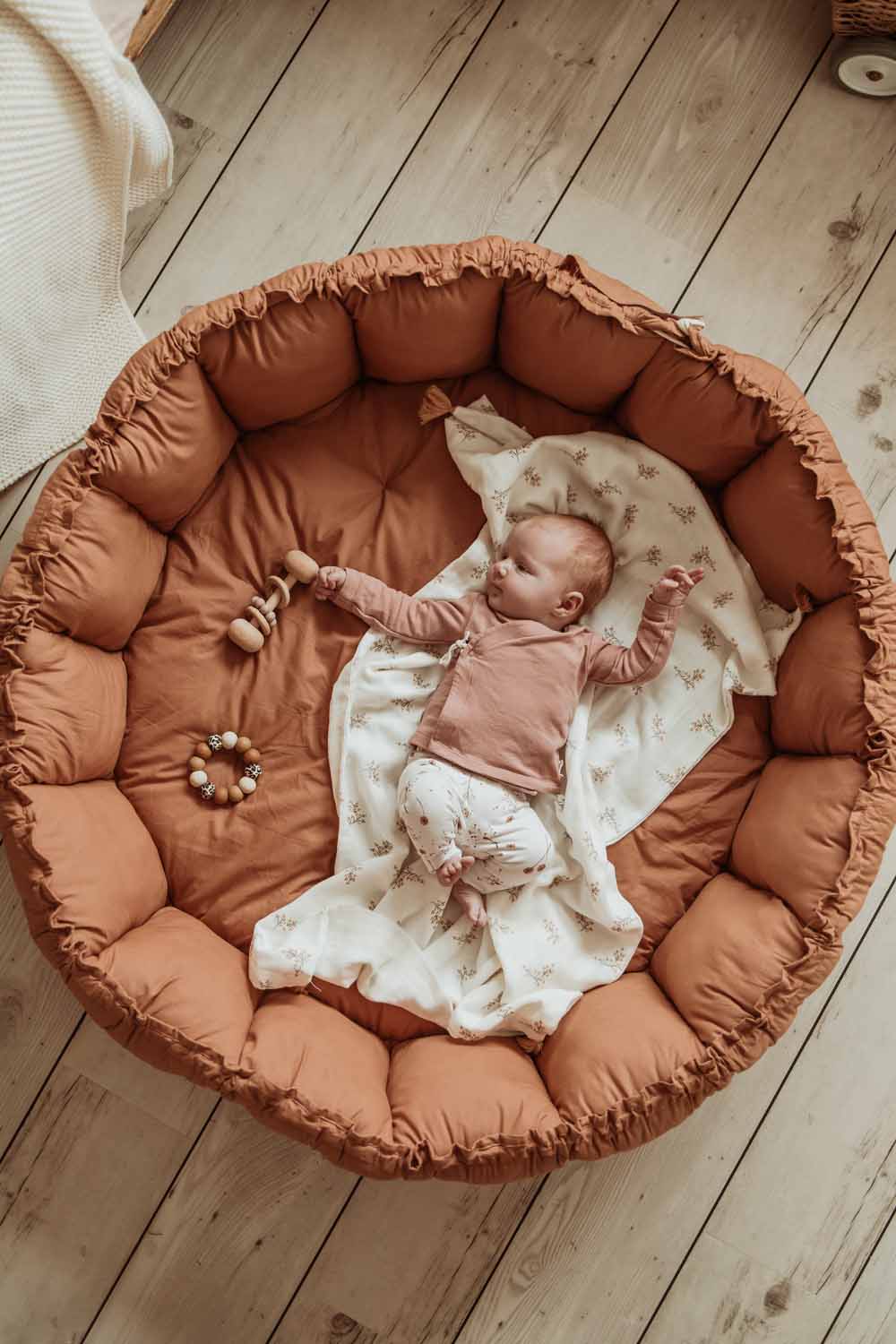 Bloom tawny brown organic babymat, raised edges, little baby sleeping on blanket on mat