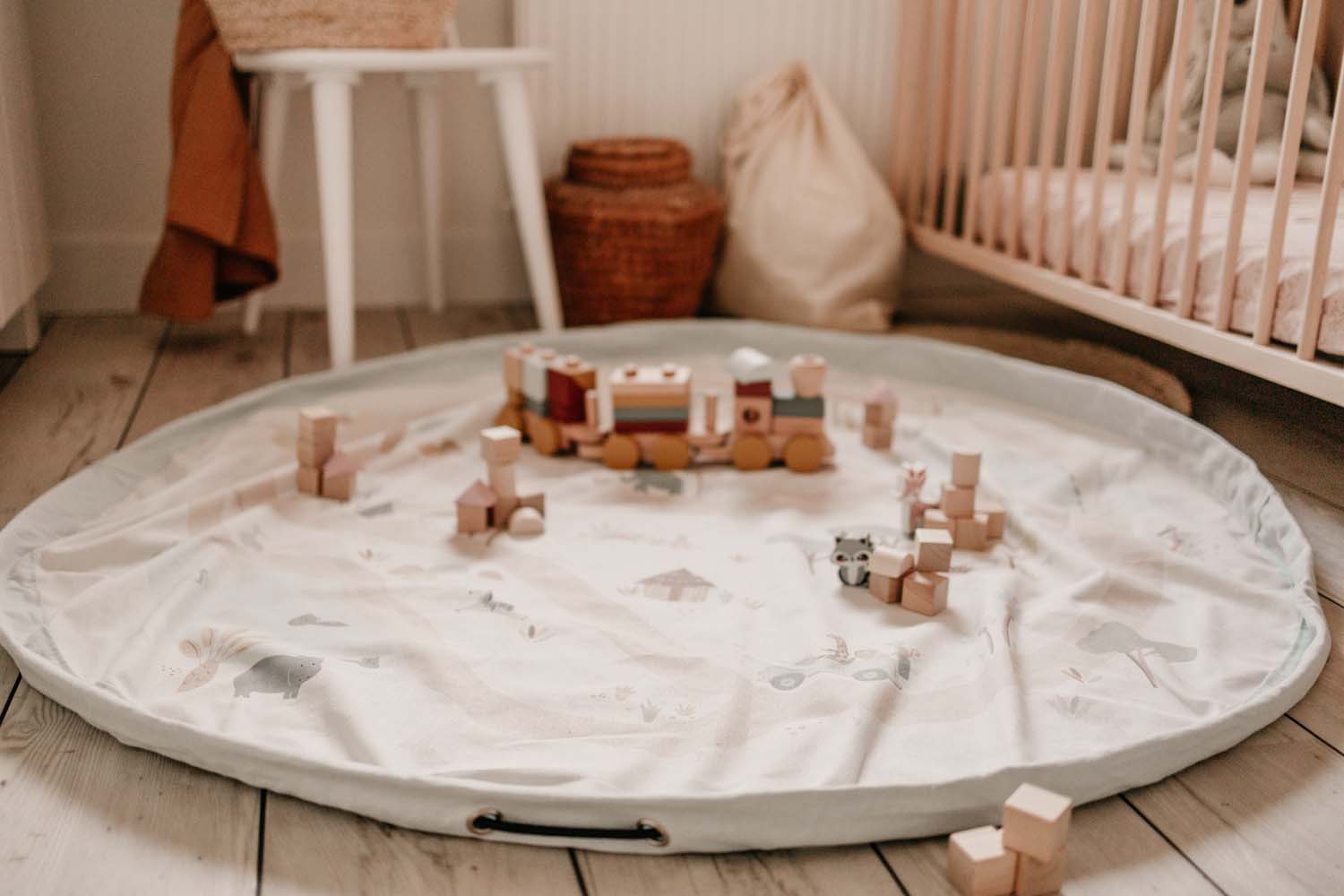 storage bag, jungle print, open of floor in kidsroom, lots of wooden toys and wooden train