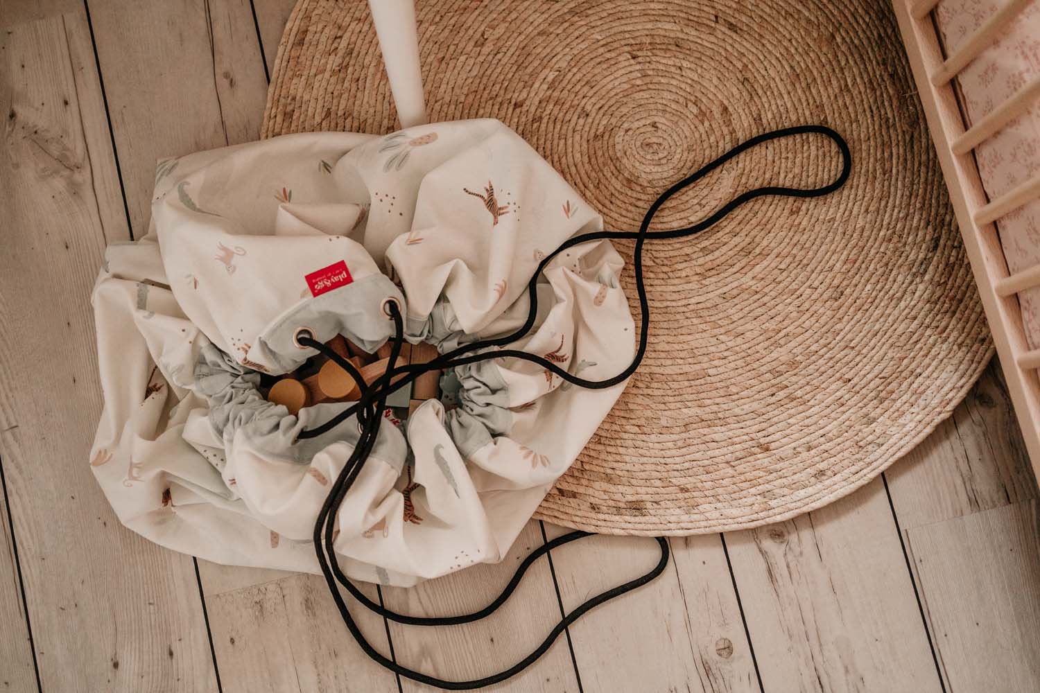 jungle storage bag, closed on floor, on carpet, filled with toys