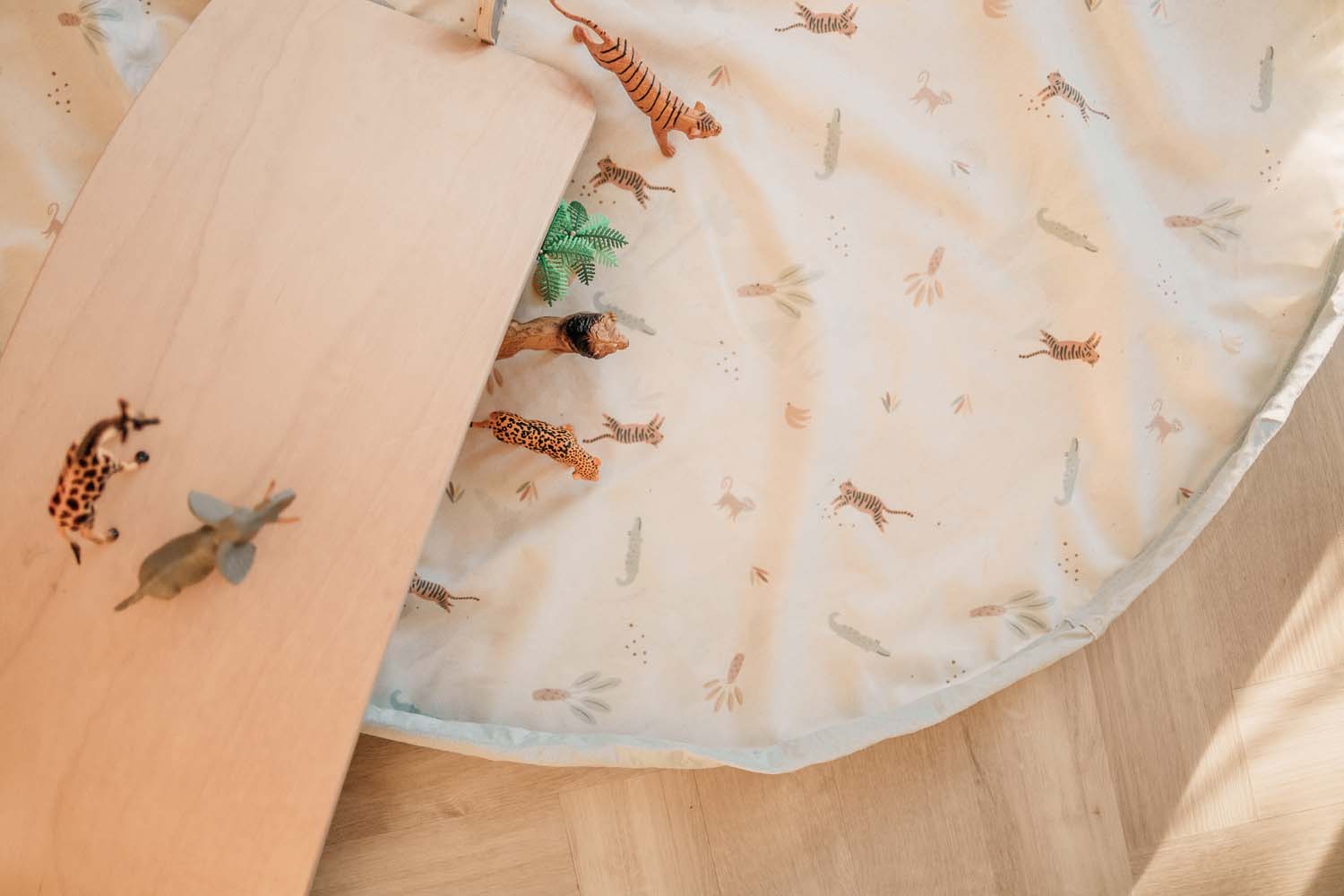 storage bag, jungle print, open of floor, lots of animal toys, wooden bridge