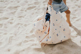 outdoor balloon storage bag and play mat, child carrying the bag while walking in the sand