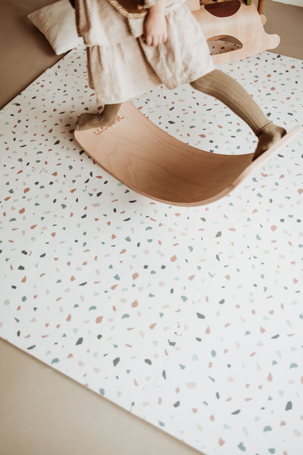 child playing with wooden slide on terrazzo puzzlemat