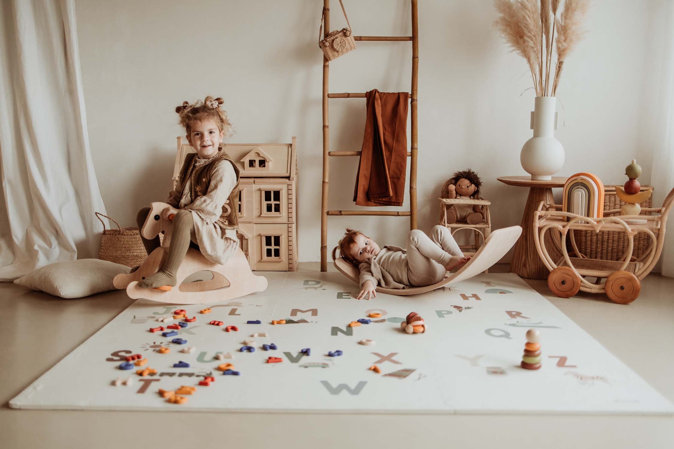 children playing with wooden rocking horse and slide on alphabet puzzlemat in kidsroom