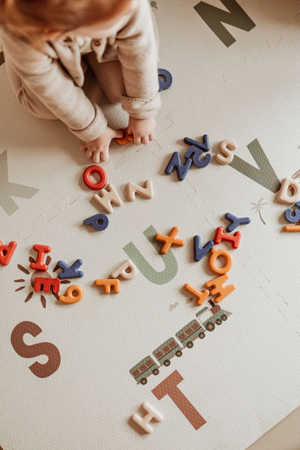 child playing with letters on alphabet puzzlemat