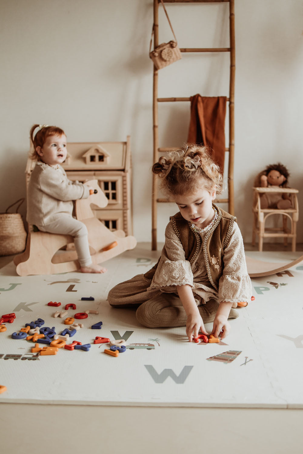 children playing with wooden rocking horse and letters on alphabet puzzlemat in kidsroom