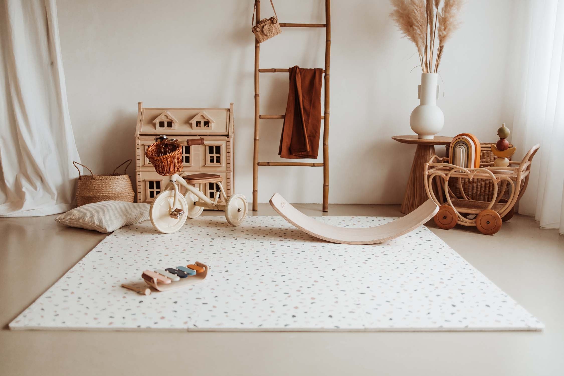 terrazzo puzzlemat on floor in kidsroom with tricycle, victorian house and wooden toys