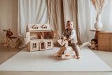 child sitting on rocking horse on dots puzzlemat in kidsroom, victorian play house and tricycle